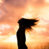 Woman looking towards the sky, hair flying behind her.