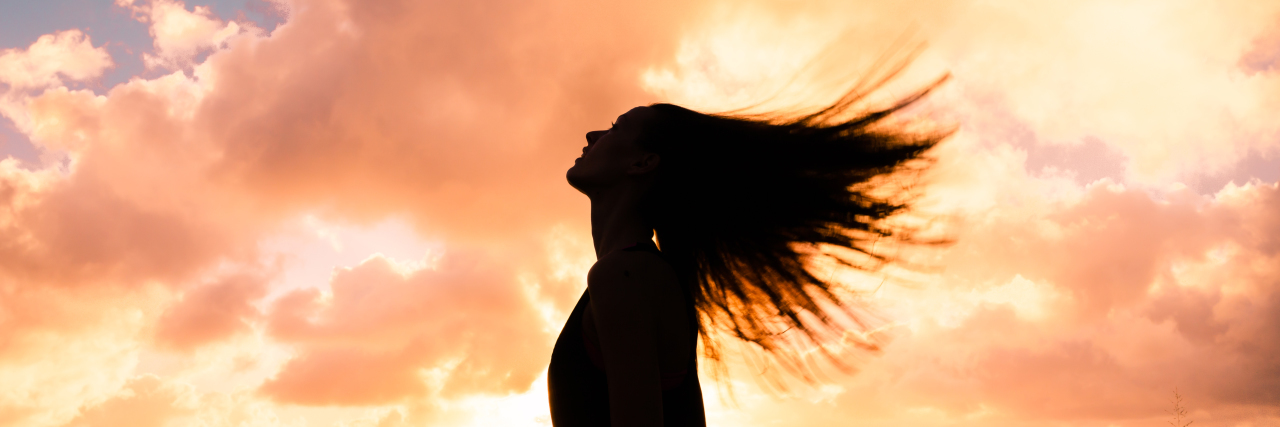 Woman looking towards the sky, hair flying behind her.