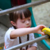Little girl with Down syndrome playing alone in a playground.