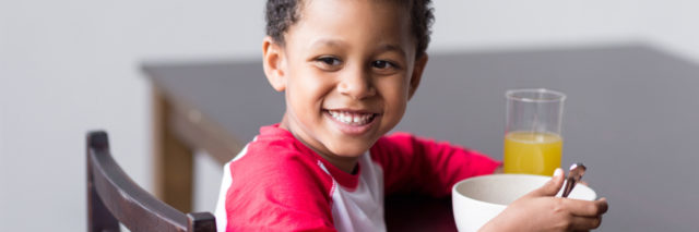 Child eating cereal smiling to the side