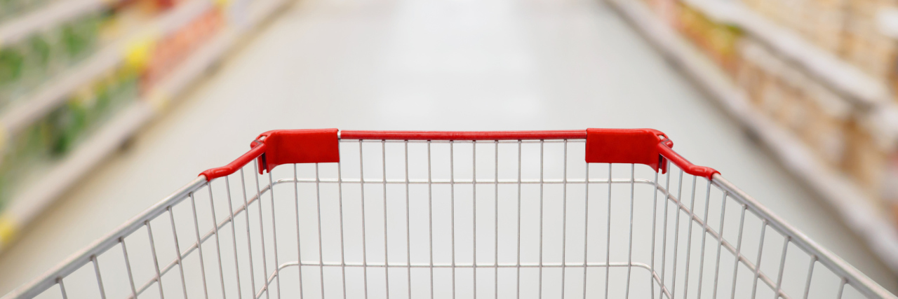 Shopping cart view in Supermarket aisle with product shelves blurred in background.