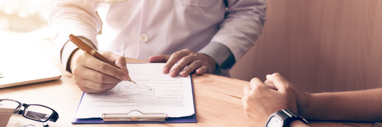 When Should I See A Psychiatrist? Doctor hand holding pen writing patient history list on note pad and talking to the patient about medication and treatment.