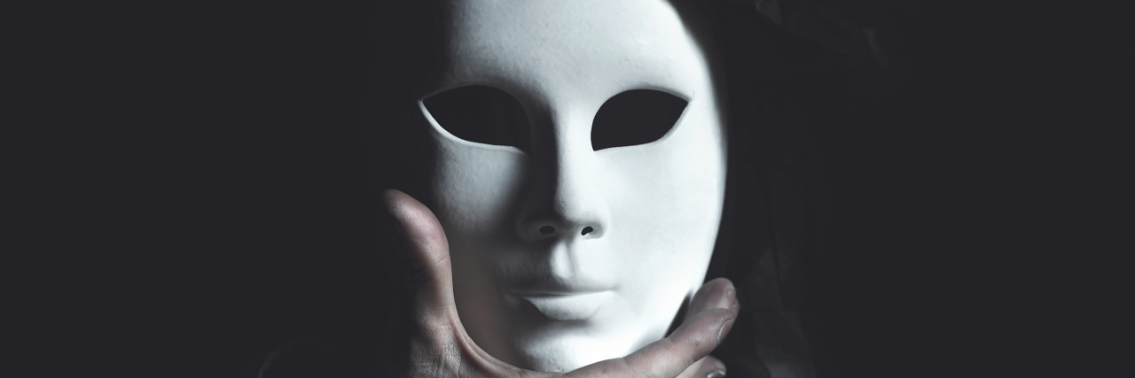 Taking Off the Mask Hiding My Autism Hands holding white mask.