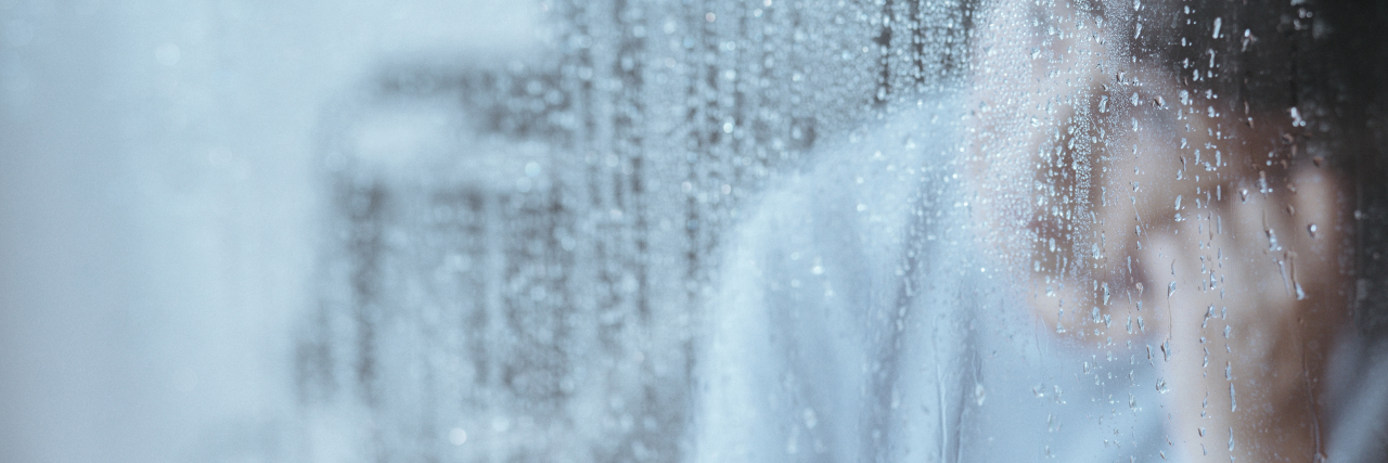 a blurred photo of an older woman sitting next to a window on a rainy day