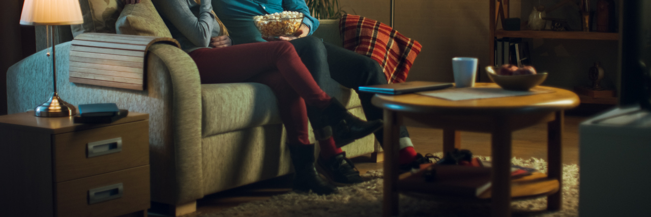 Why I Choose to Ignore Social Pressure And Care For My Migraines First Man and woman sitting on the coach eating popcorn