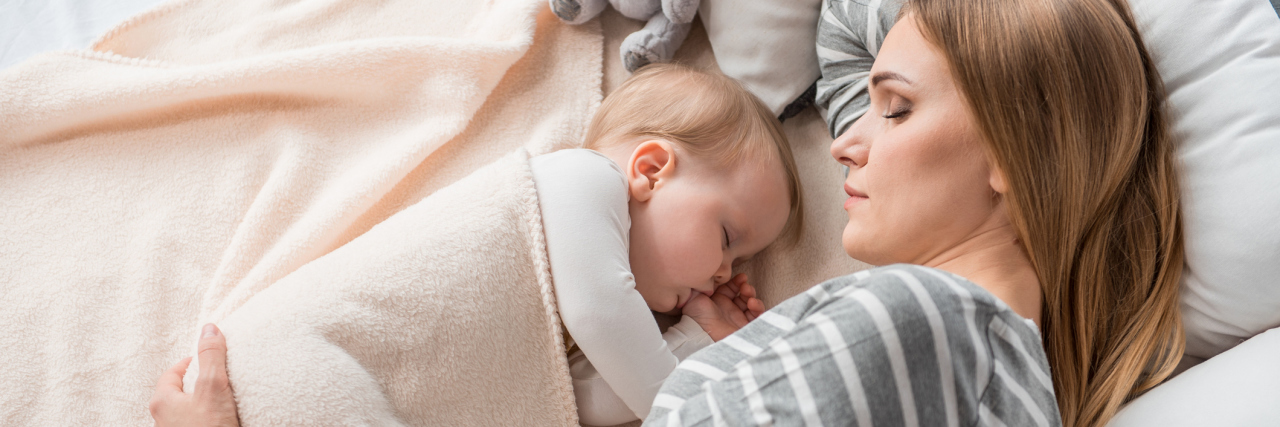 How to Practice Self-Care When You're a Mom With Chronic Illness mom sleeping in bed next to her baby