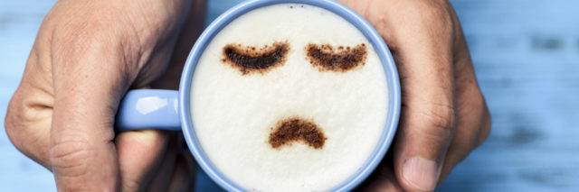 man with a cup of cappuccino with a sad face