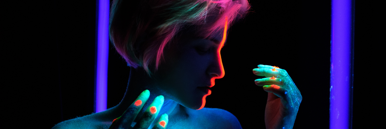 Accepting My Sensory Sensitivities Woman with rainbow glow paint and rainbow hair.