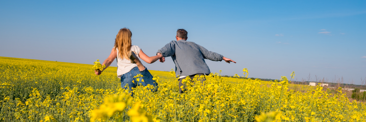 Romantic couple running through a field.