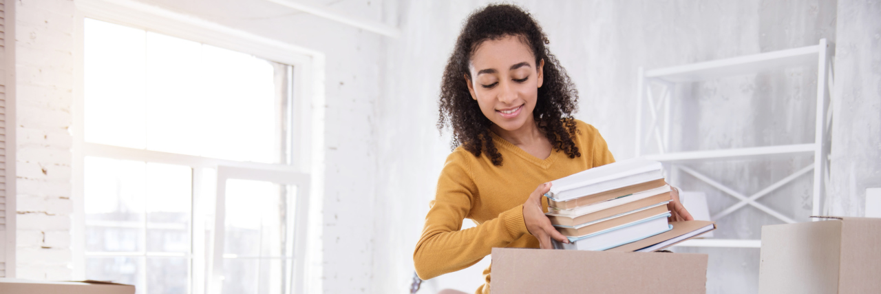 Tips for Moving Away From Home With Allergies and Anaphylaxis young woman unpacking boxes