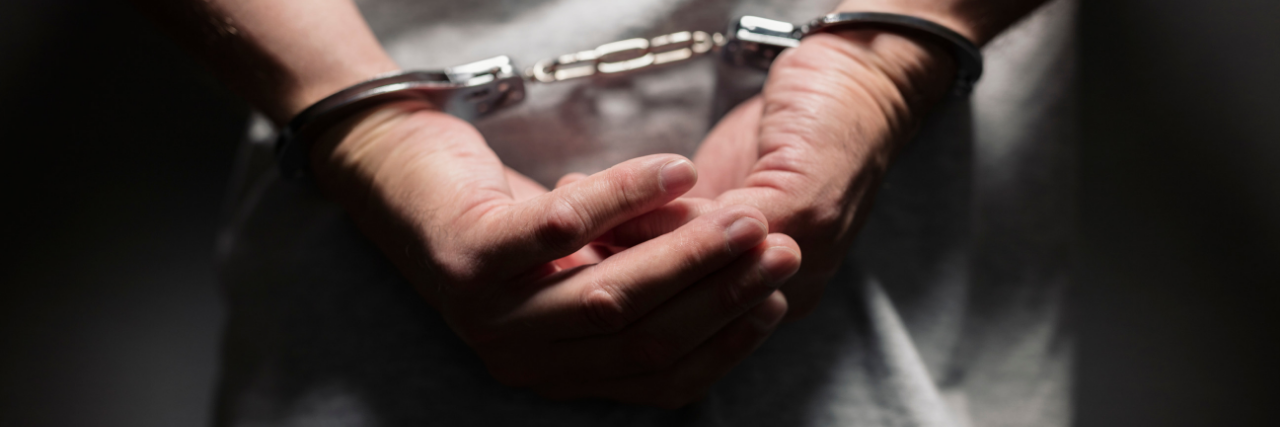 Close up of man's hands handcuffed behind his back