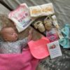 Baby girl with Down syndrome sleeping. Arranged around her are items form Brittany's Baskets of Hope.