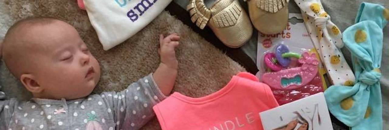 What 665 Babies With Down Syndrome Have Taught Me Baby girl with Down syndrome sleeping. Arranged around her are items form Brittany's Baskets of Hope.