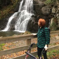 the author standing with her walker by a waterfall