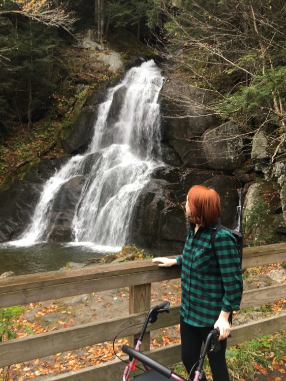the author standing with her walker by a waterfall