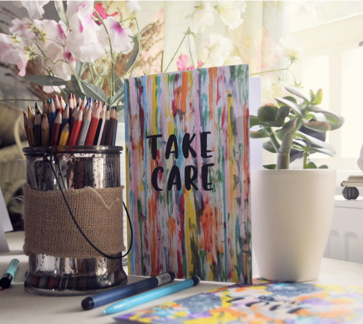 Card with abstract, colorful background with the words "take care" in black.