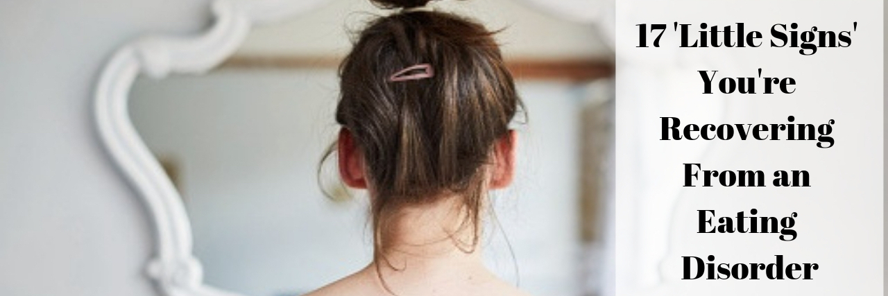 'Little Signs' You're Recovering From an Eating Disorder A woman looking at a mirror.