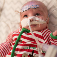 a baby boy with a Christmas themed outfit in the hospital
