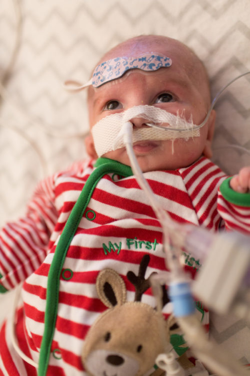 a baby boy with a Christmas themed outfit in the hospital