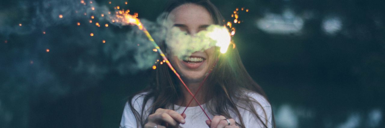 young woman holding sparklers and smiling
