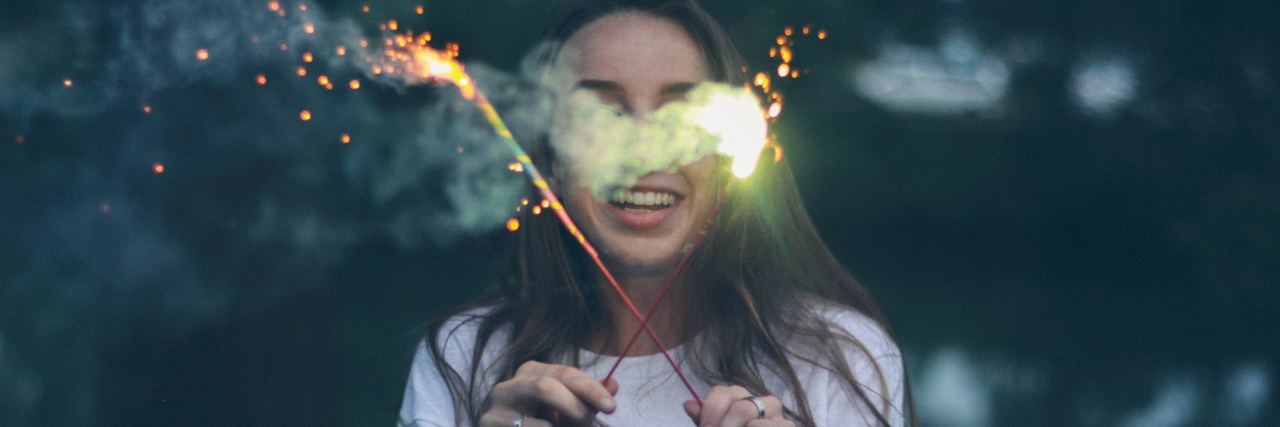 How to Celebrate 'Small' Accomplishments With Depression young woman holding sparklers and smiling