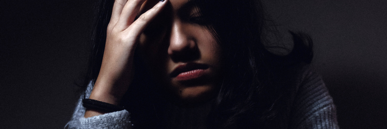 depressed woman sitting in front of mug with head resting on hand