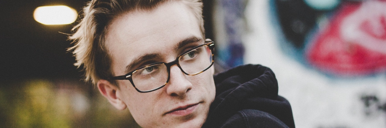 15 Signs You Grew Up With 'Depression Irritability' A young man with glasses looking away from the camera