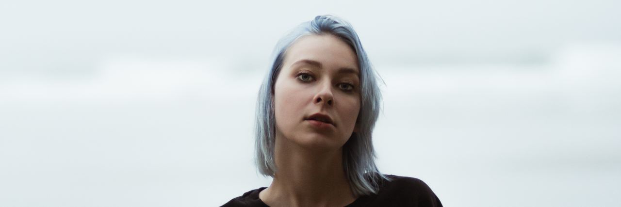 How My Childhood Trauma Affects Seemingly 'Simple' Choices Woman with light blue hair standing outside and staring at camera