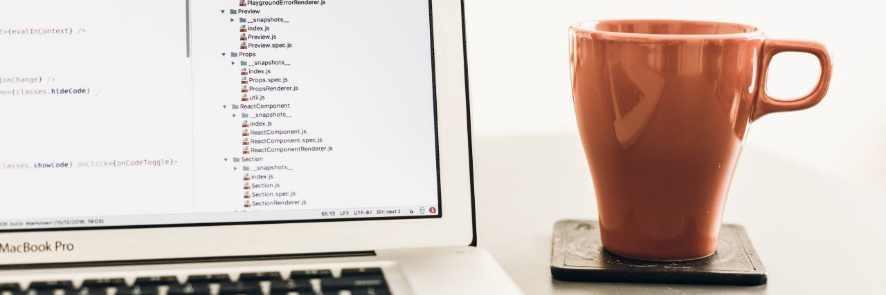 9 Work From Home Jobs Available in Canada or the U.K. Open laptop with text onscreen on a table next to a red coffee mug on a coaster