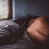 woman lying in bed beside window asleep and facing away