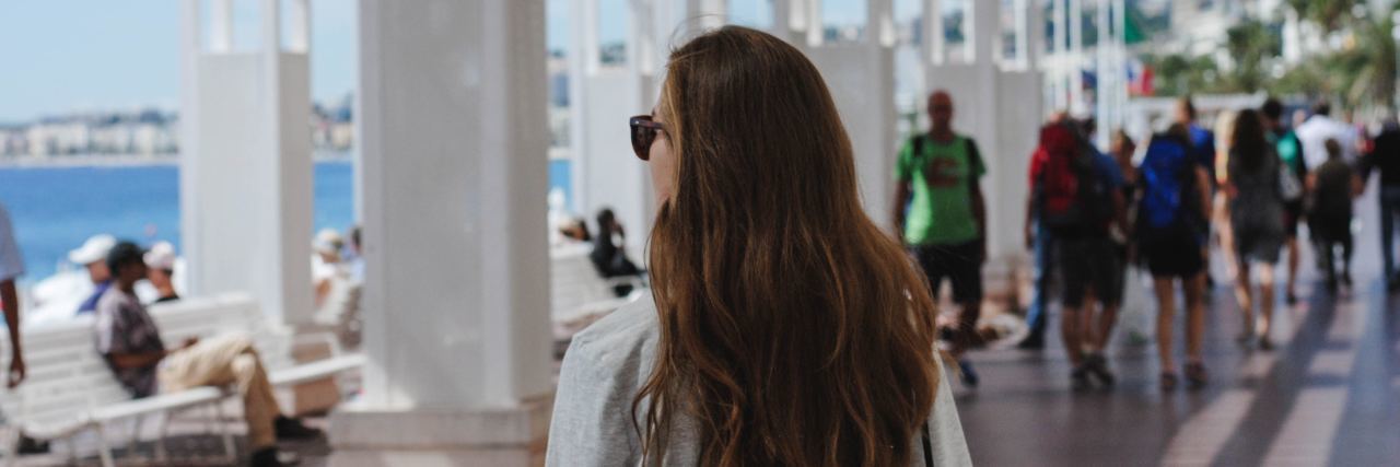 Tips for Traveling With Allergies and Anaphylaxis woman with long dark hair standing outside near the ocean