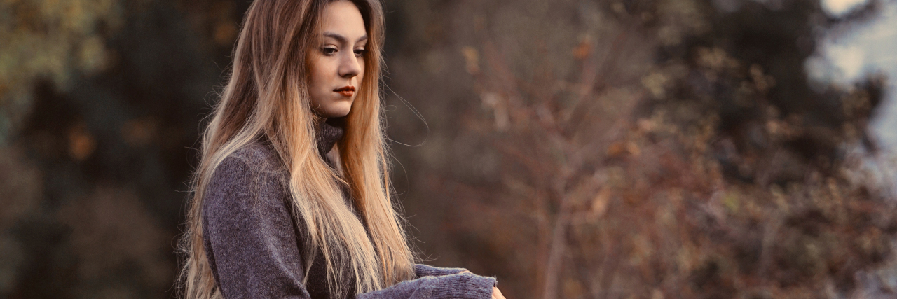 Someone Told Me I Was Too Smart to Self-Harm young woman with blonde hair standing at bridge by trees