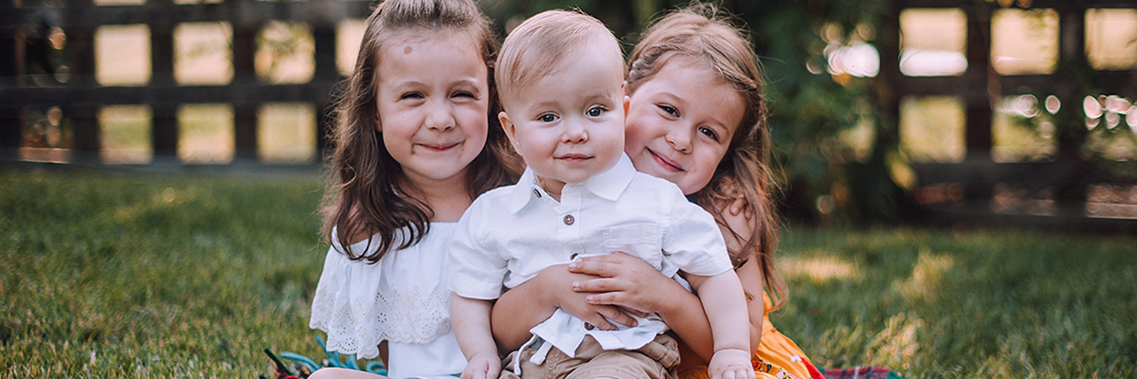 Why Early Detection of Cerebral Palsy Matters Owen with his two sisters sitting in the grass.