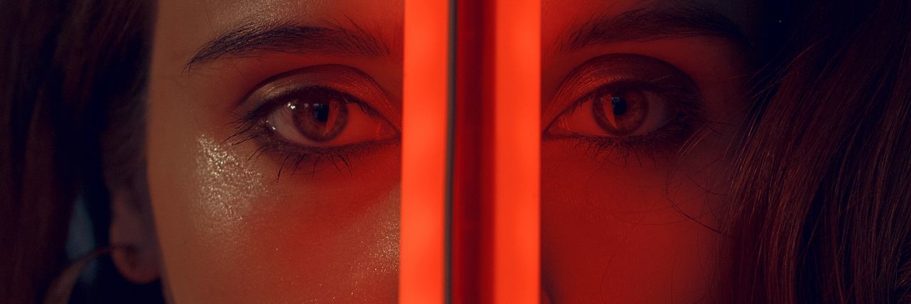 The Different Types of 'Splitting' in Borderline Personality Disorder close up photo of woman looking into camera with red light in her face