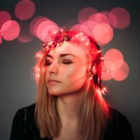 photograph of blonde woman with red fairy lights around her head and blurred red bokeh effect with lights out of focus