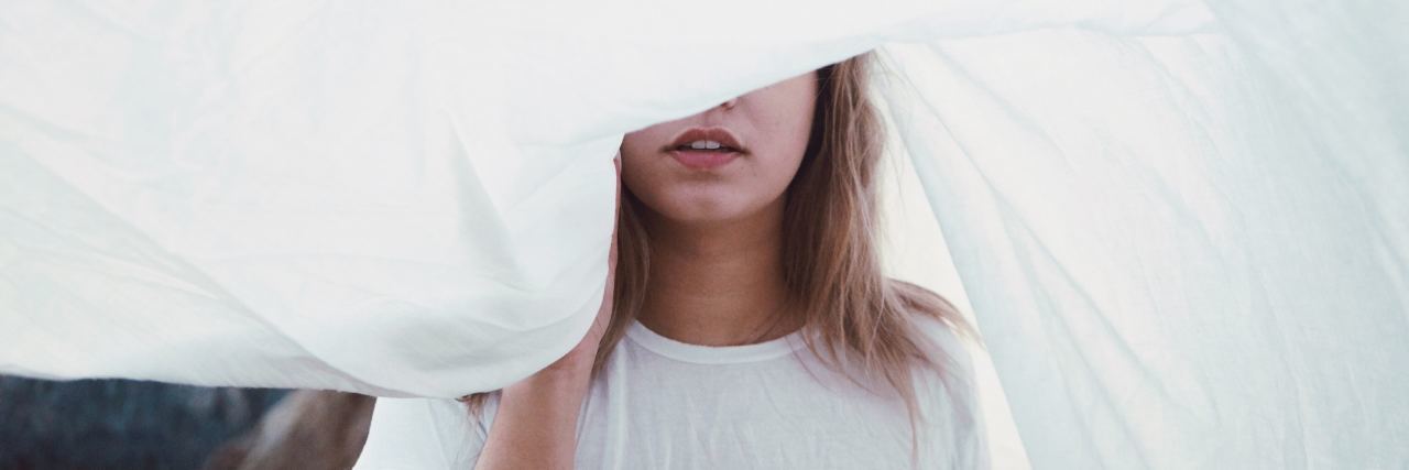 photo of blonde woman with part of upper face hidden by white sheet