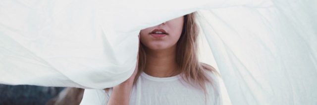 photo of blonde woman with part of upper face hidden by white sheet