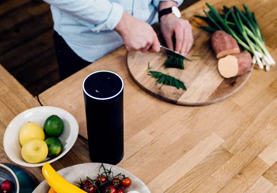 Person cooking with an Amazon Echo on the table nearby.