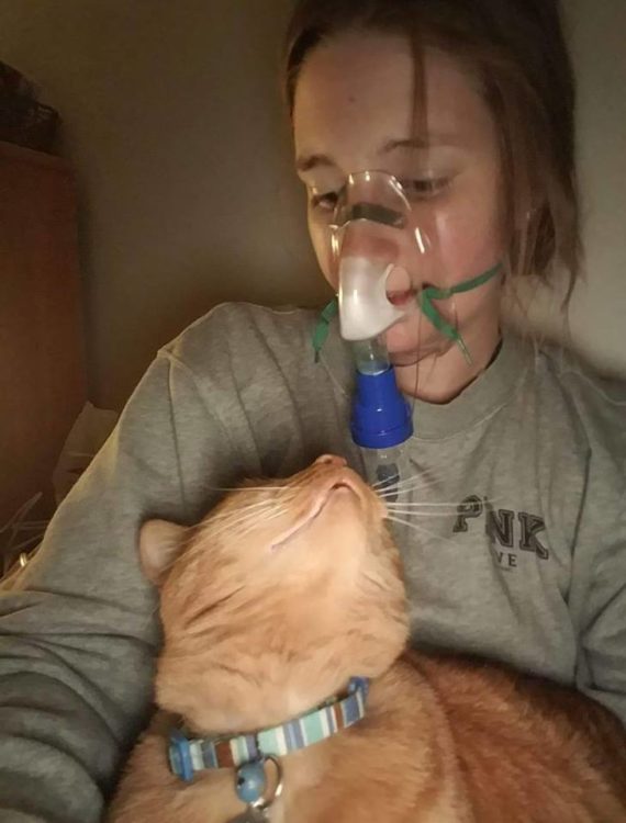 woman wearing a face mask and sitting with her cat