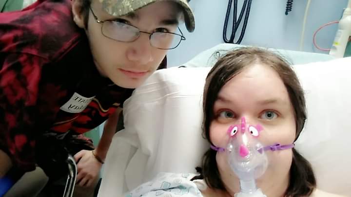 woman lying in a hospital bed with her boyfriend standing next to her