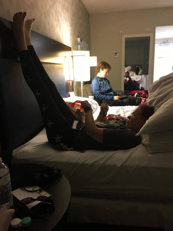 woman lying on bed with feet against the wall in a hotel room