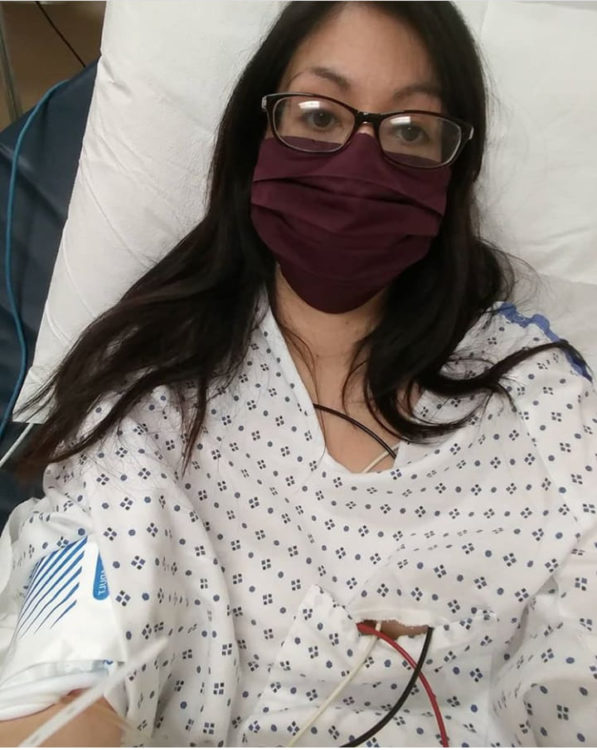 woman wearing surgical mask in hospital bed