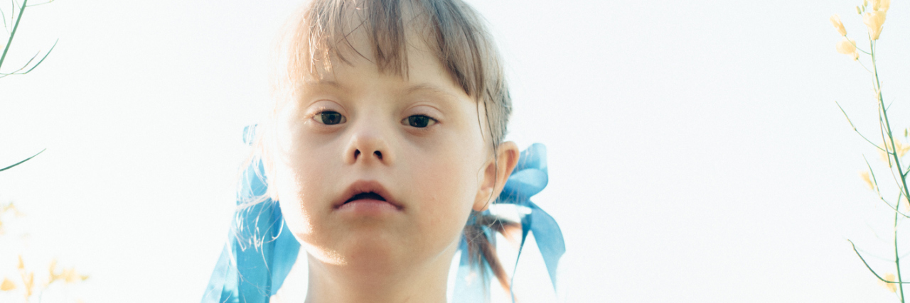 Doctor's Perceptions Affect the Care They Provide for My Daughter Little girl with Down syndrome outdoors looking at camera.