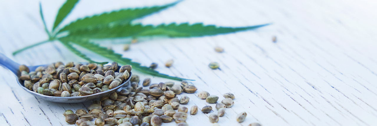 Congress’ U.S. Farm Bill Legalizes Hemp With Implications for CBD hemp leaves on wooden background, seeds, cannabis oil extracts in jars