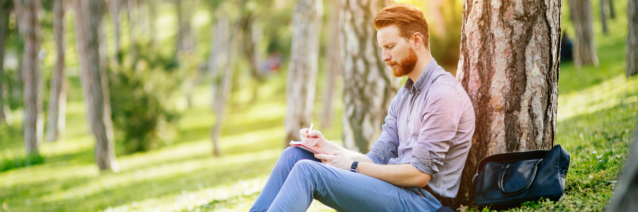 Developing Emotional Intelligence as a Person With Autism Man in park writing in journal.