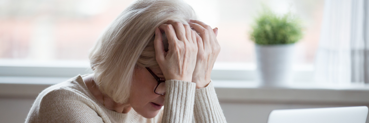Ehlers Danlos Syndrome and Losing Executive Dysfunction woman holding head in hands, frustrated, near computer and cup of tea