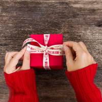 A woman's hands holding a red holiday gift box