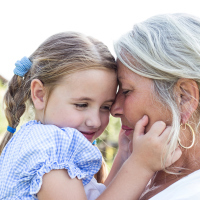 An older woman holding a small girl, they're heads are close together