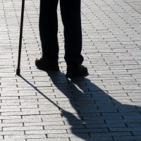 Silhouette of man walking with a cane.