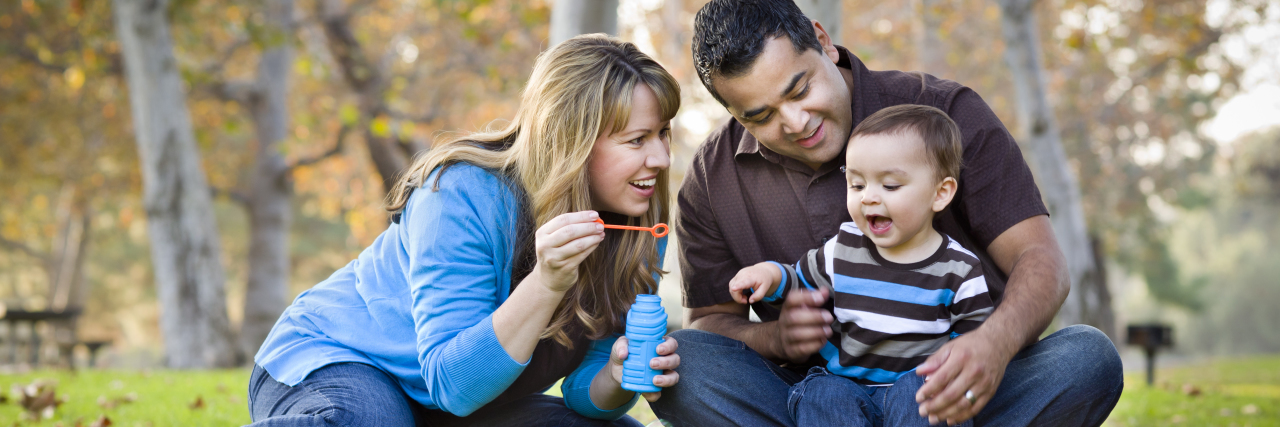 Young family blowing bubbles in a park in autumn.